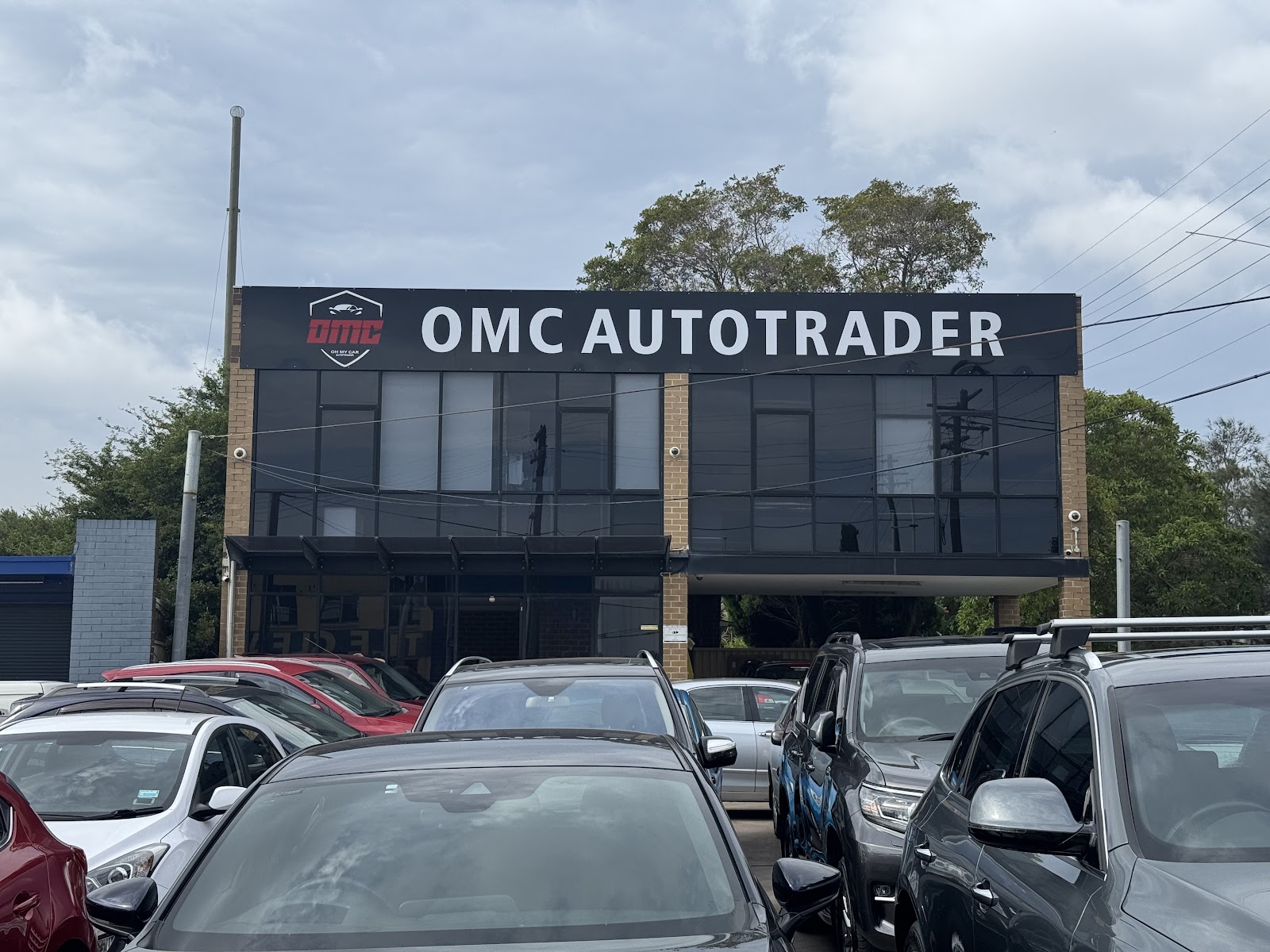 The OMC Autotrader building from Parramatta Road, with cars parked across the front
